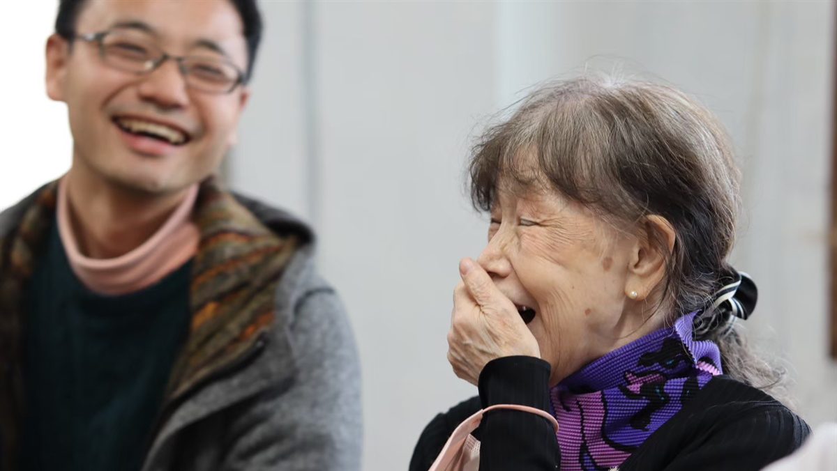 学生とシニアの女性が、声を出して笑い合っている様子