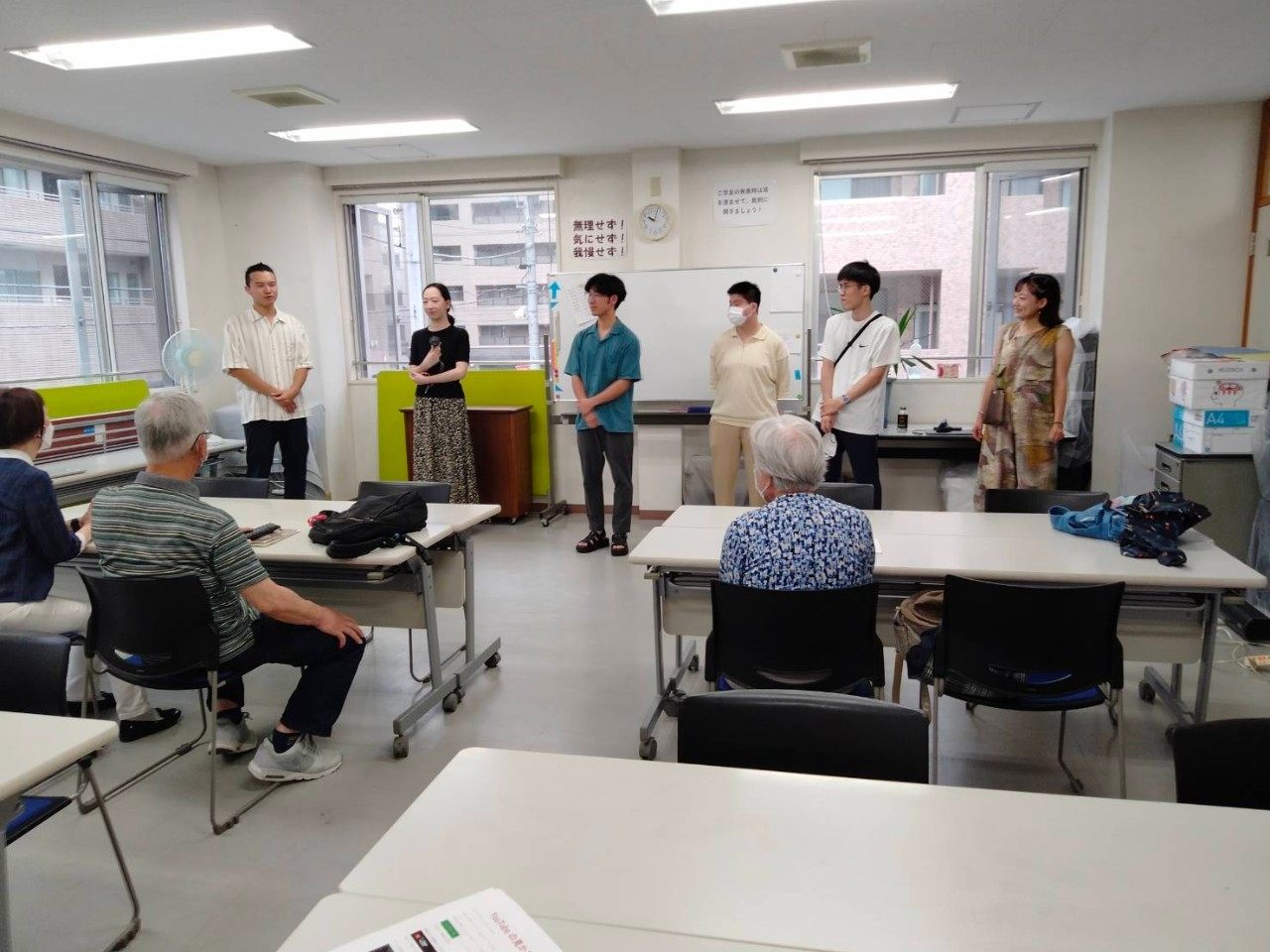 会議室でメンバーがシニアの前で自己紹介をしている様子